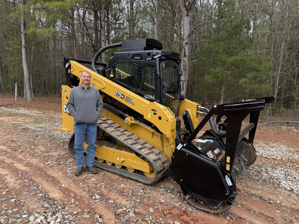 TerraGrade owner standing with a Cat skid steer forestry mulcher
